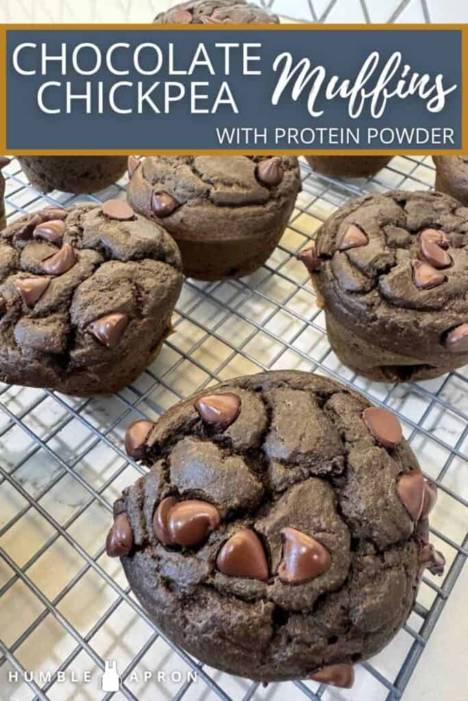 Chocolate chip muffins with chickpeas and protein powder rest on a wire cooling rack. Chocolate chips are visible on the tops of the moist, dark brown muffins. A recipe label is overlaid at the top.